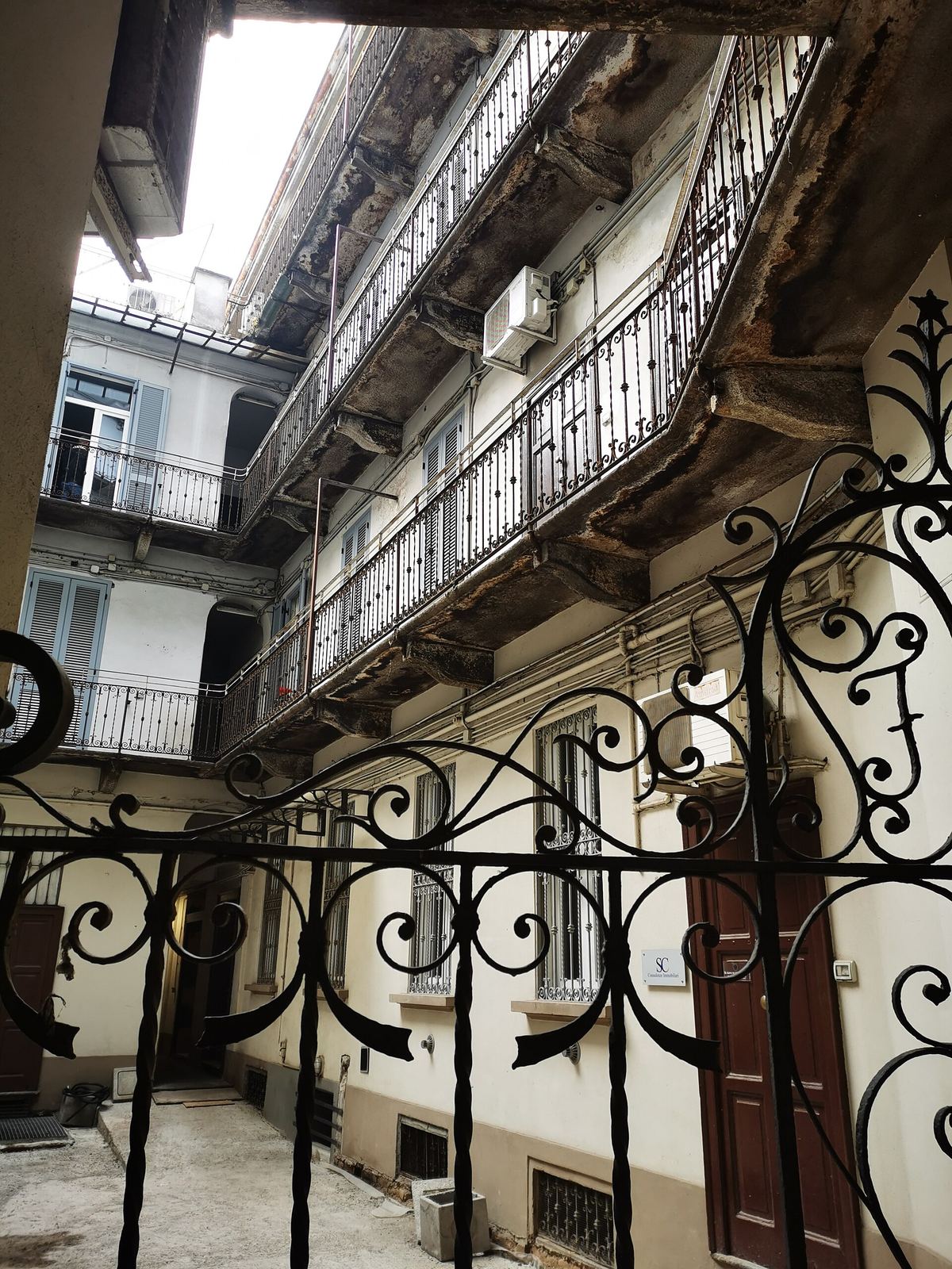 Il cancello in ferro battuto e i ballatoi di una casa di ringhiera in via Michelangelo Buonarroti, a Milano